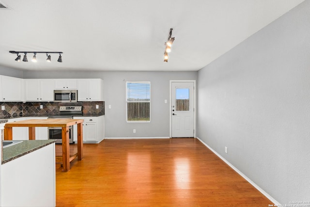 kitchen with light wood-type flooring, stainless steel appliances, backsplash, and white cabinets