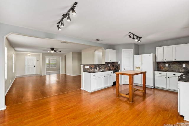 kitchen featuring white appliances, light wood finished floors, white cabinets, dark countertops, and open floor plan