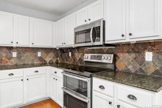 kitchen featuring dark stone countertops, stainless steel appliances, tasteful backsplash, and white cabinetry