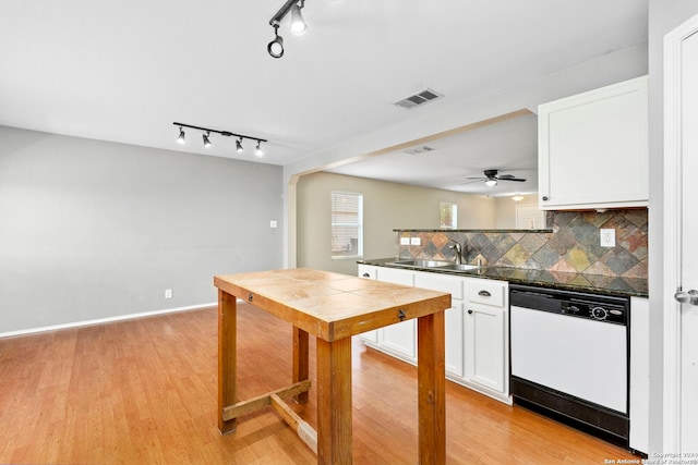 kitchen featuring dark countertops, white cabinets, dishwasher, and a sink