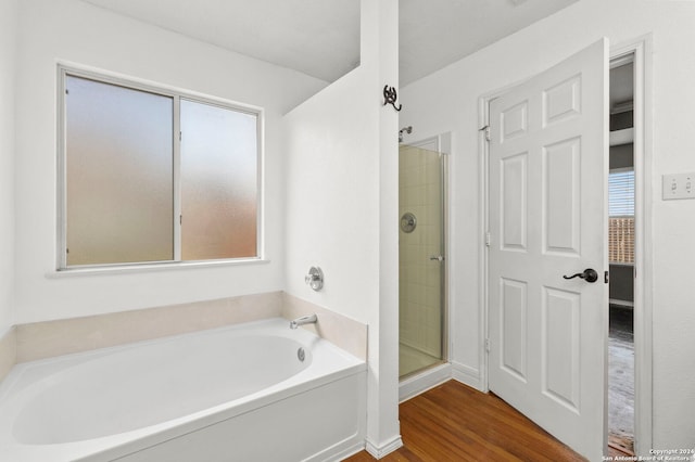 bathroom featuring a stall shower, a garden tub, and wood finished floors