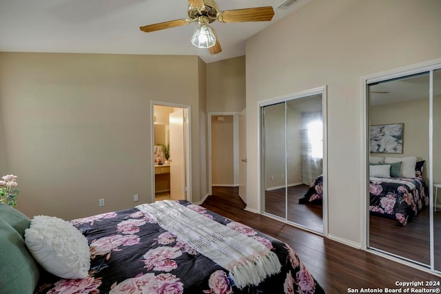 bedroom with dark hardwood / wood-style floors, ensuite bath, multiple closets, lofted ceiling, and ceiling fan