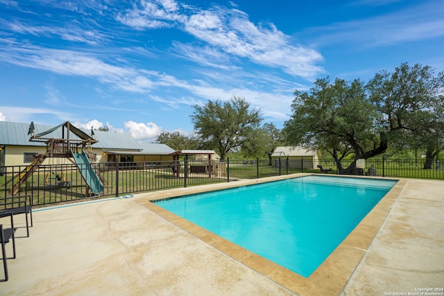 view of pool featuring a lawn, a patio area, and a playground