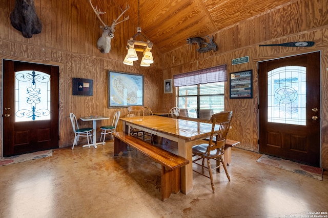 dining space with concrete flooring, a wealth of natural light, wooden walls, and wood ceiling