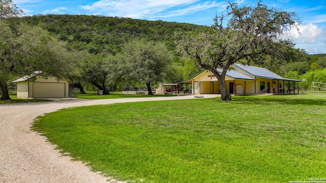 201 N Tomahawk Way, Concan, TX 78801 - view of front of house featuring curved driveway, a front yard, an outbuilding, a carport, and a view of trees