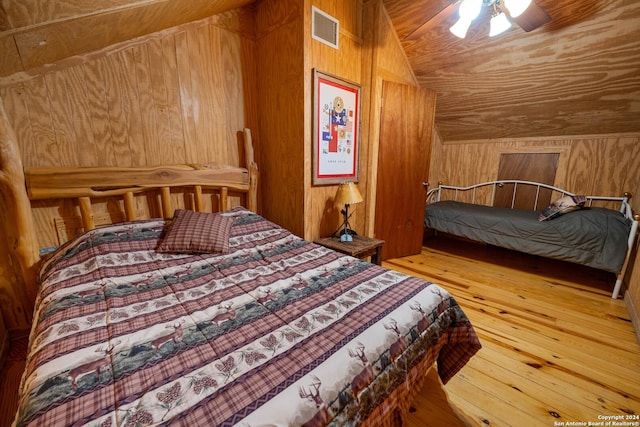 bedroom featuring hardwood / wood-style floors, ceiling fan, lofted ceiling, and wood walls