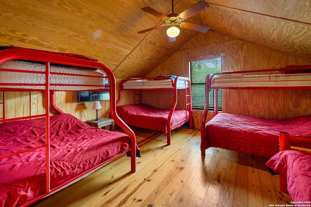 bedroom featuring ceiling fan, wood walls, hardwood / wood-style floors, vaulted ceiling, and wood ceiling