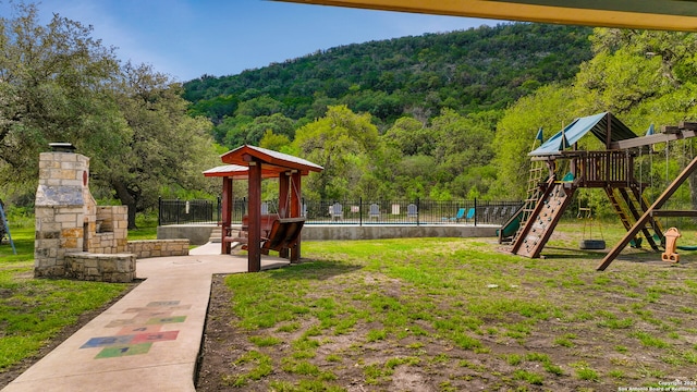 exterior space featuring a playground, a mountain view, and a swimming pool