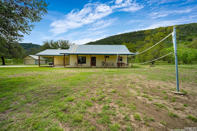 201 N Tomahawk Way, Concan, TX 78801 - view of front of house featuring metal roof, a detached garage, a front yard, and a view of trees
