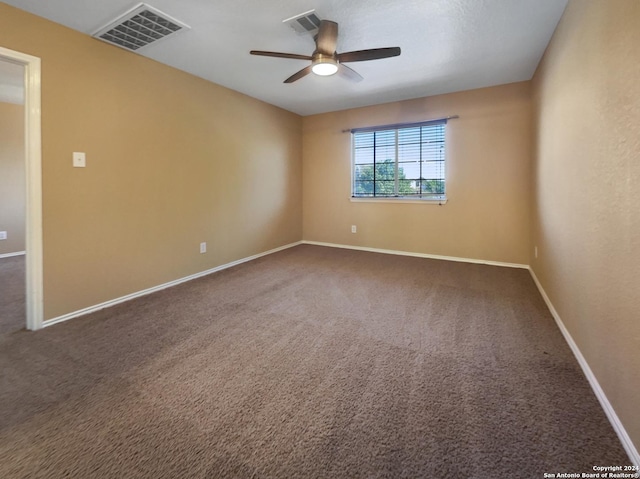 carpeted spare room with baseboards, visible vents, and ceiling fan