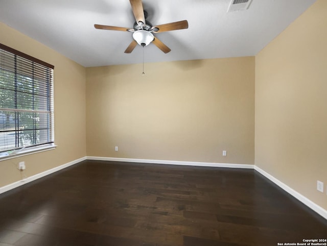 empty room with visible vents, a ceiling fan, baseboards, and dark wood-style flooring