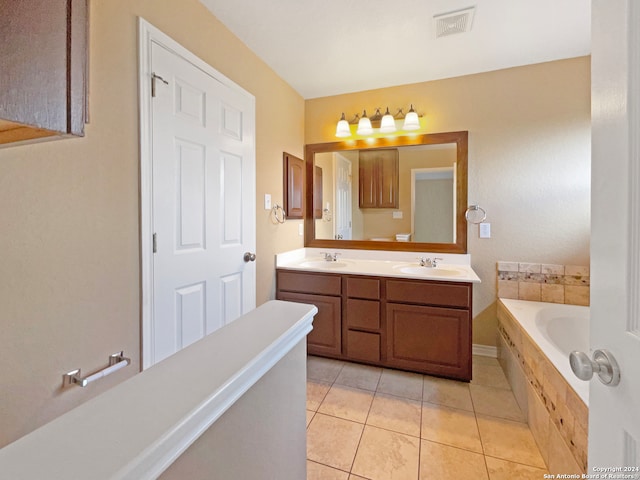 bathroom featuring tiled tub, vanity, and tile patterned floors