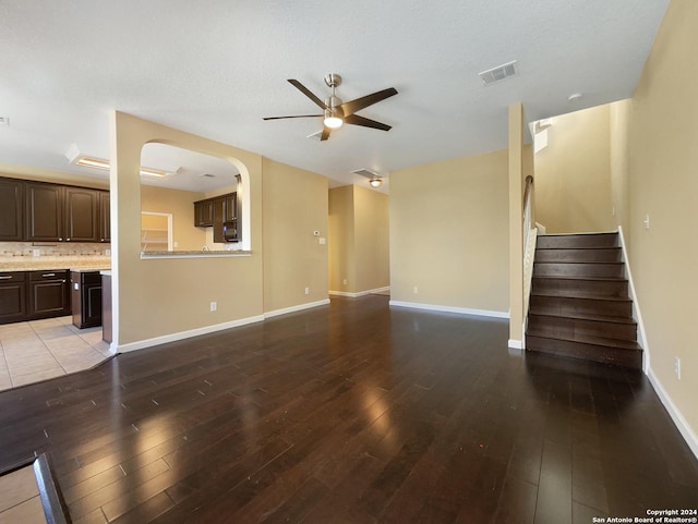 unfurnished living room with visible vents, baseboards, ceiling fan, stairs, and wood finished floors