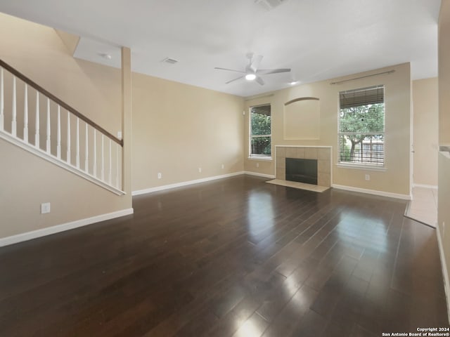 unfurnished living room with ceiling fan, dark hardwood / wood-style floors, and a tile fireplace