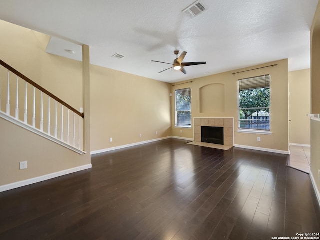 unfurnished living room with visible vents, baseboards, ceiling fan, a tiled fireplace, and wood finished floors