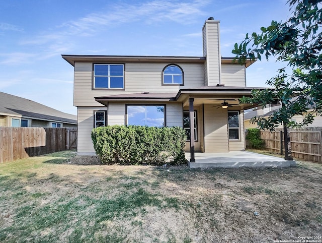 back of house featuring a ceiling fan, a chimney, fence private yard, a patio area, and a lawn