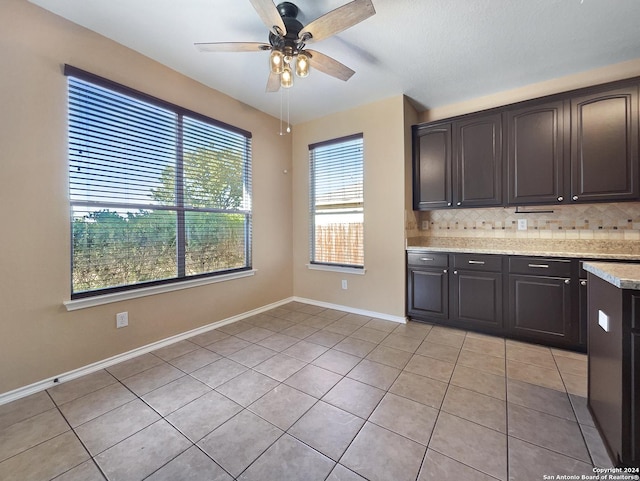 kitchen with a ceiling fan, backsplash, light tile patterned floors, baseboards, and dark brown cabinets