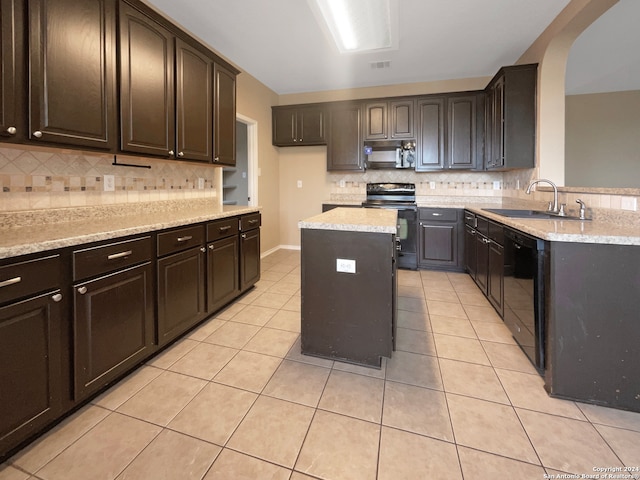 kitchen with a kitchen island, black appliances, light tile patterned floors, sink, and light stone counters