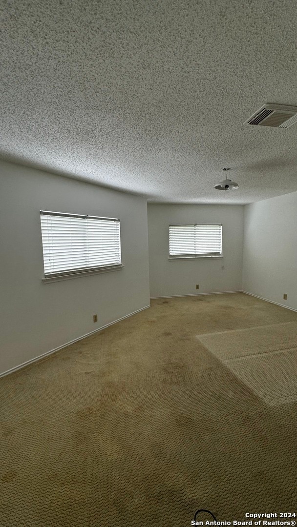 carpeted empty room featuring a textured ceiling