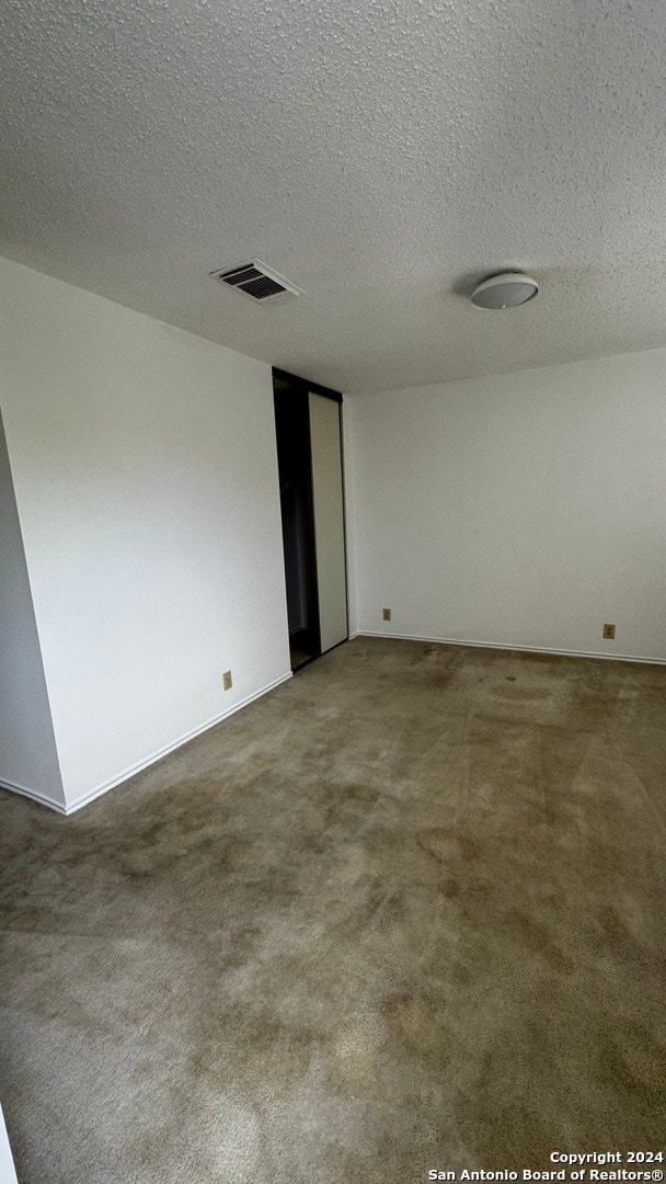 carpeted spare room with a textured ceiling