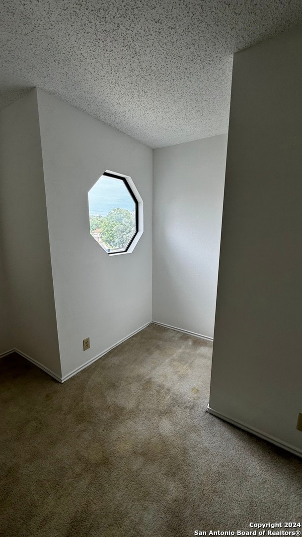 empty room with a textured ceiling and carpet