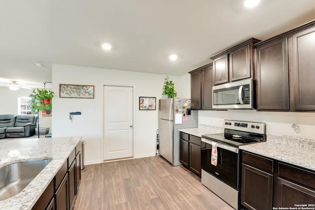 kitchen featuring light hardwood / wood-style flooring, light stone counters, ceiling fan, appliances with stainless steel finishes, and dark brown cabinetry