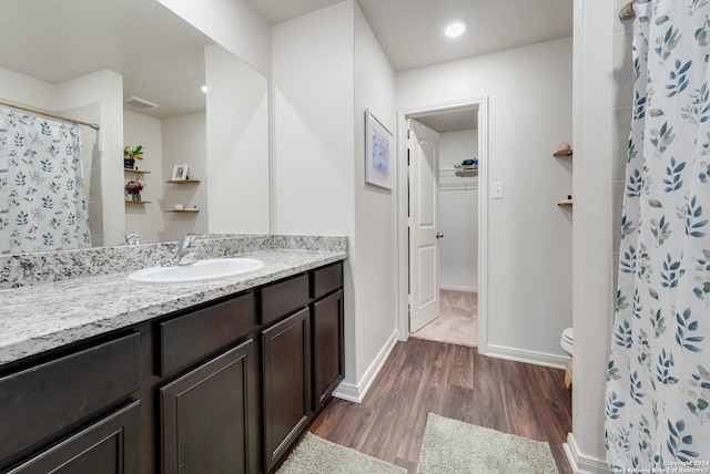 bathroom featuring wood-type flooring, toilet, walk in shower, and vanity