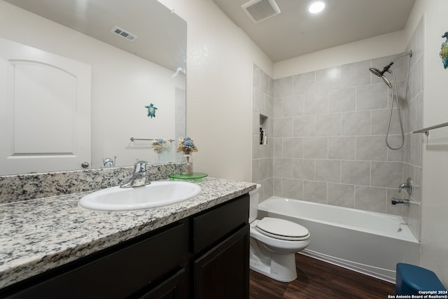 full bathroom with vanity, toilet, tiled shower / bath combo, and hardwood / wood-style floors