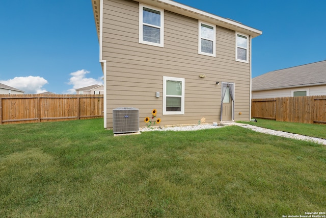 back of house featuring central air condition unit and a yard