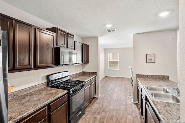 kitchen featuring light wood-type flooring, stainless steel appliances, sink, dark brown cabinetry, and a textured ceiling