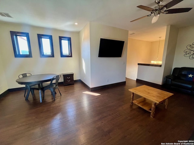 living room with ceiling fan with notable chandelier and dark hardwood / wood-style flooring