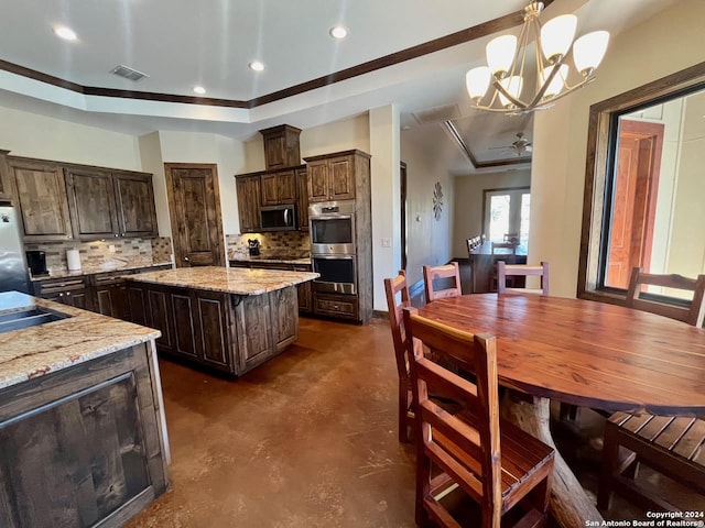 kitchen with dark brown cabinetry, pendant lighting, backsplash, stainless steel appliances, and light stone countertops