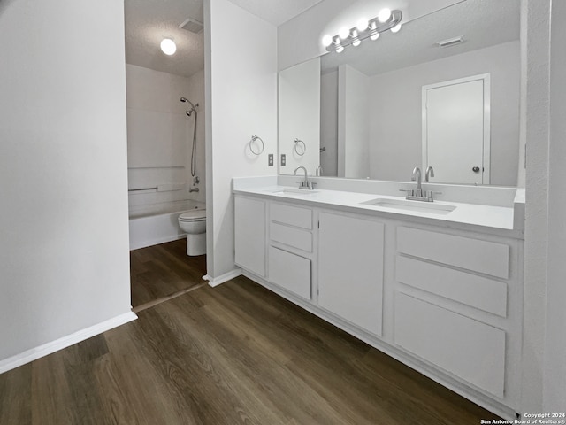 full bathroom featuring hardwood / wood-style flooring, toilet, shower / bath combination, vanity, and a textured ceiling