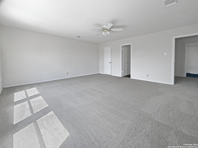 unfurnished bedroom with ceiling fan, light colored carpet, and a textured ceiling