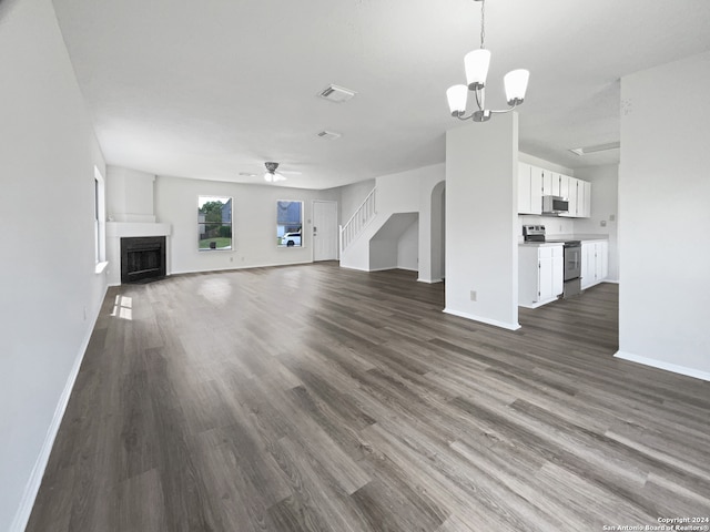 unfurnished living room with ceiling fan with notable chandelier and dark hardwood / wood-style floors