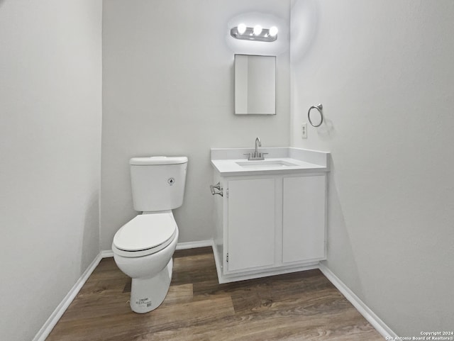 bathroom with hardwood / wood-style floors, toilet, and vanity