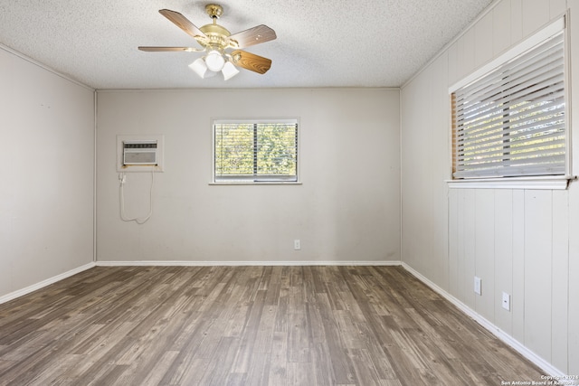 spare room featuring a wall mounted AC, dark hardwood / wood-style flooring, a textured ceiling, and ceiling fan