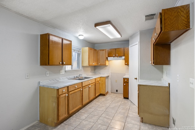 kitchen featuring light tile patterned flooring, sink, and a textured ceiling