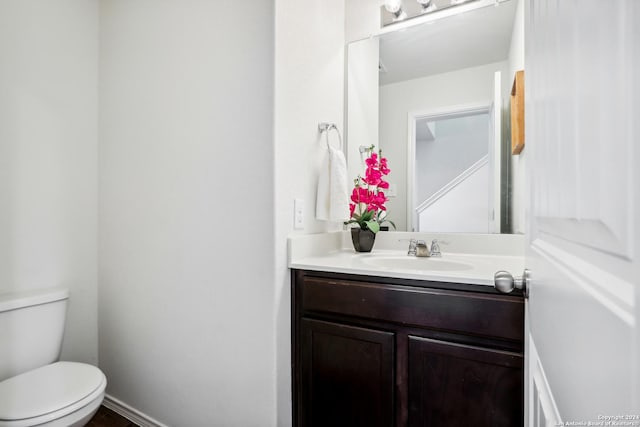 half bath with toilet, vanity, and baseboards