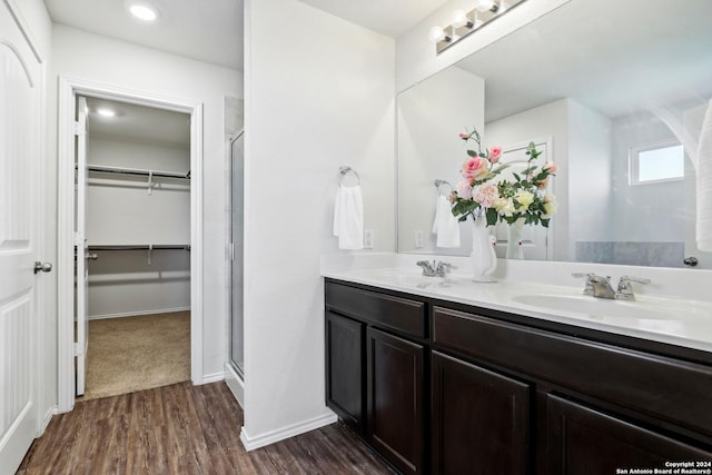 bathroom with a shower stall, wood finished floors, a walk in closet, and a sink