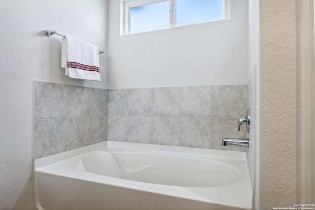 bathroom with a bath and a textured wall