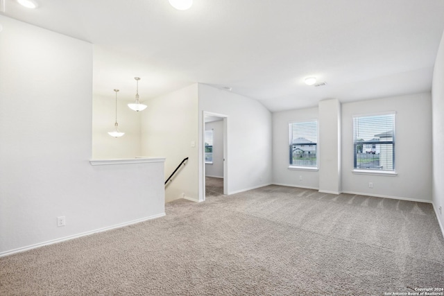 carpeted empty room featuring vaulted ceiling and baseboards