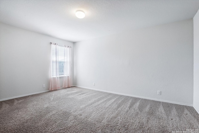 carpeted spare room featuring baseboards