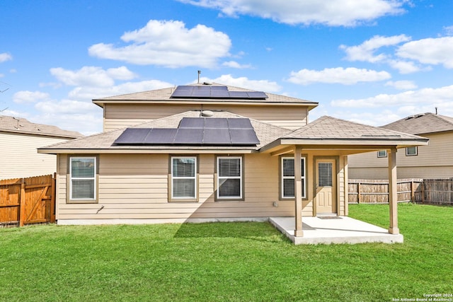 back of property featuring a fenced backyard, roof mounted solar panels, a yard, and roof with shingles