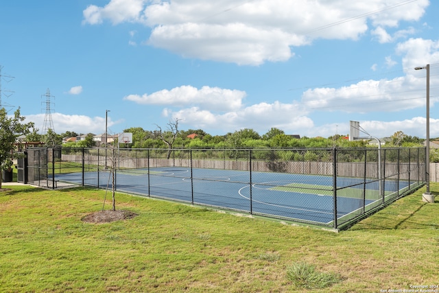 view of tennis court featuring basketball hoop and a yard