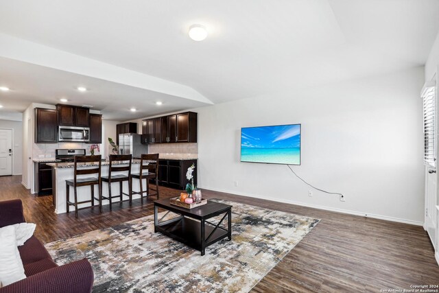 kitchen with decorative backsplash, appliances with stainless steel finishes, light wood-type flooring, and a kitchen island with sink