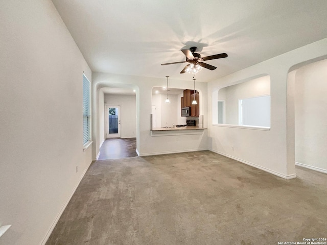 unfurnished living room featuring arched walkways, baseboards, a ceiling fan, and carpet floors