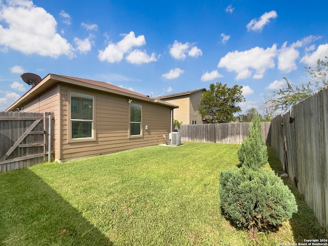 rear view of property with central air condition unit and a yard