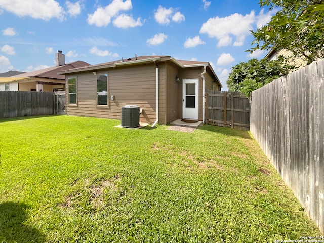 back of house featuring a yard and central AC