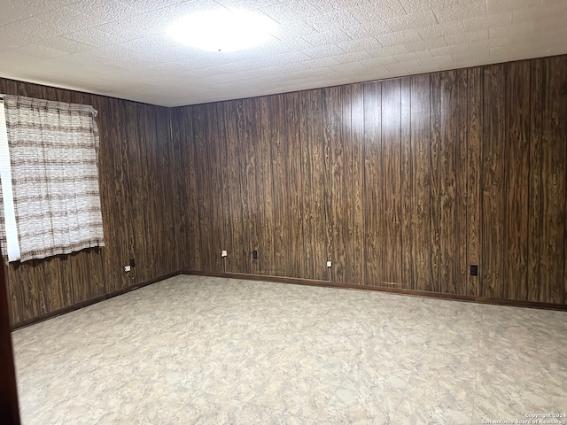 unfurnished room featuring wooden walls